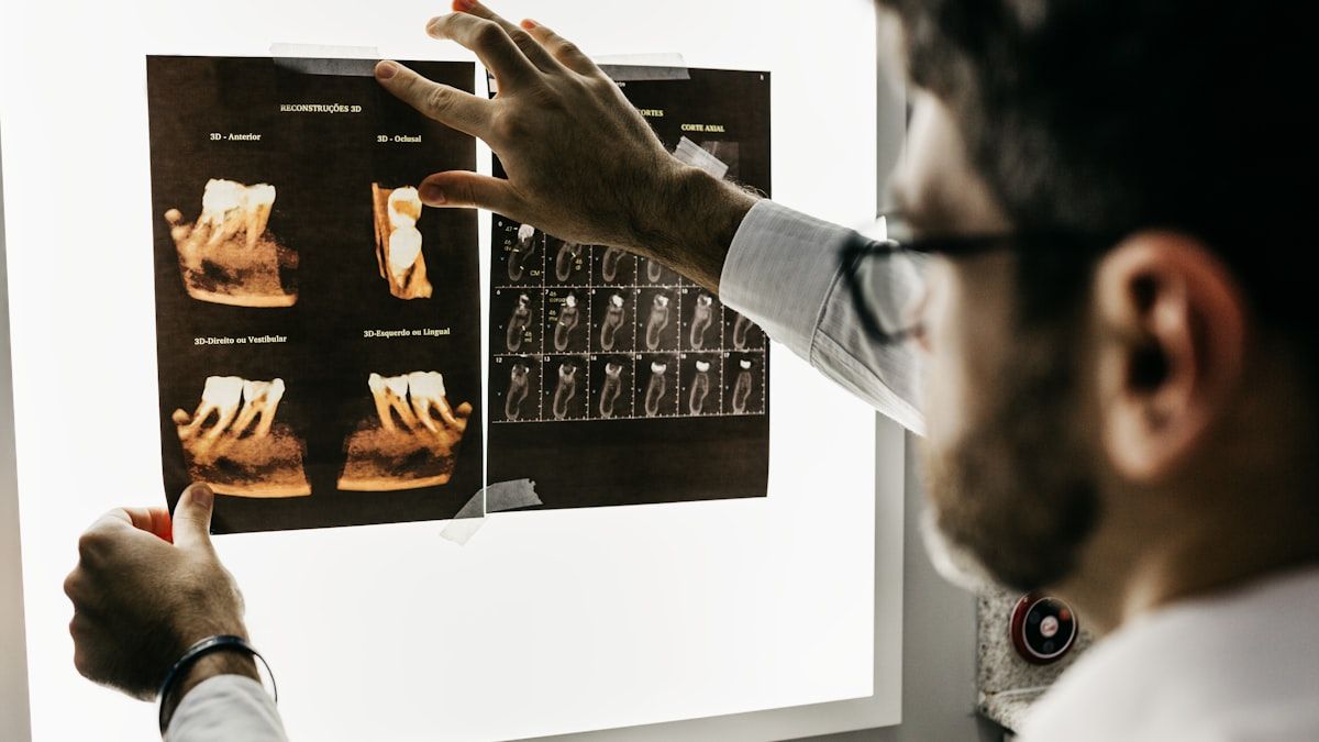Dentista revisando radiografías y estudios del expediente clínico en un negatoscopio